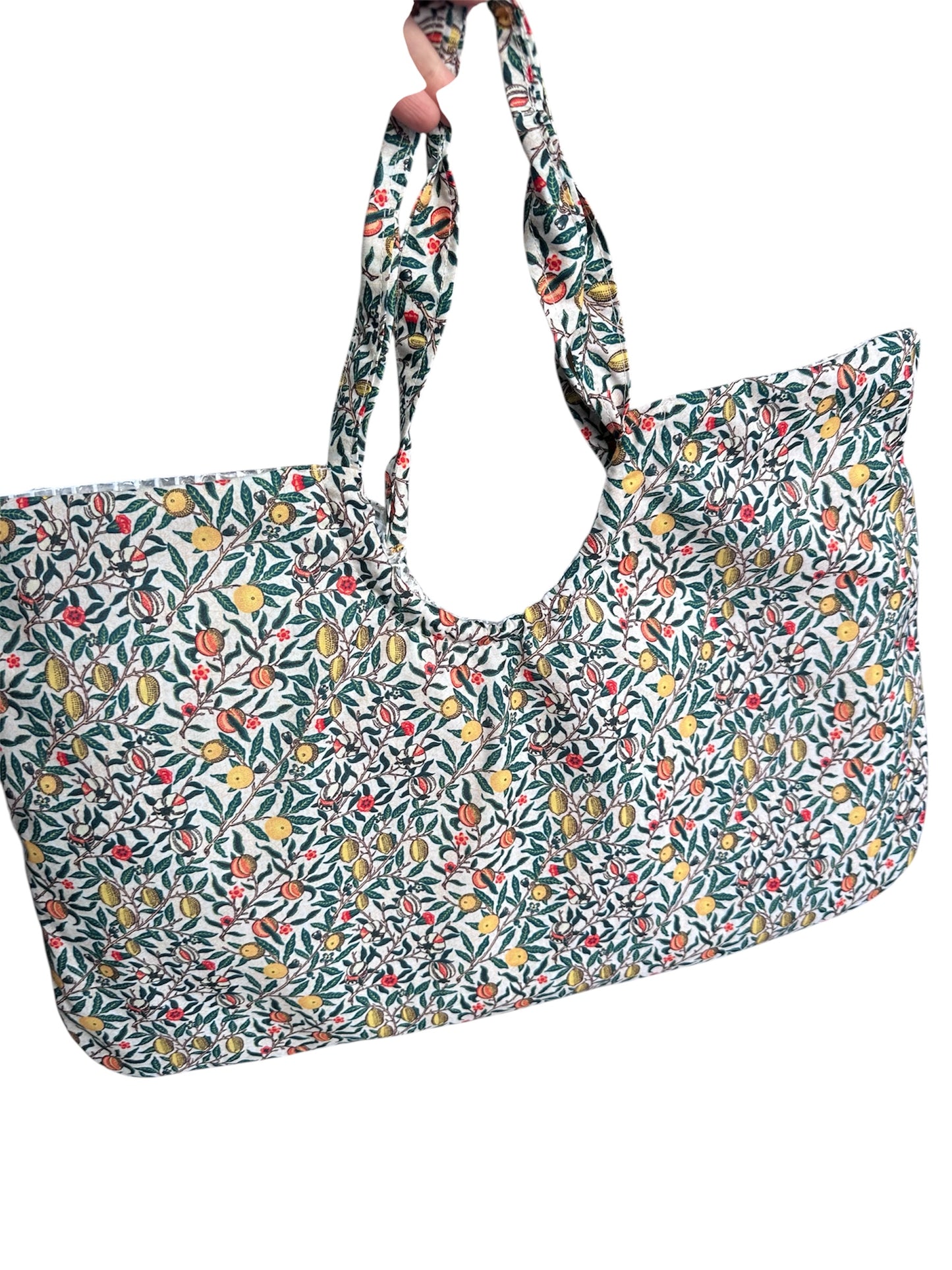 Close-up of a large handmade cotton tote bag featuring a William Morris inspired fruit and botanical print with lemons, pomegranates, oranges and green leaves on a white background, with matching fabric twisted handles